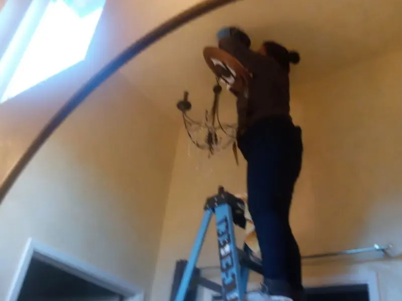 Electrician installing a chandelier in a Lytle residence